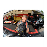 A motorcyclist adjusting protective gear in a garage.